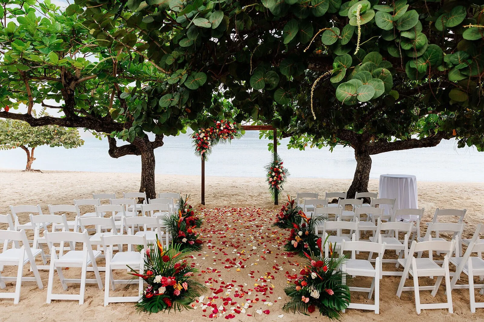 Beach wedding ceremony setup with white chairs and floral arch at S Hotel Montego Bay.