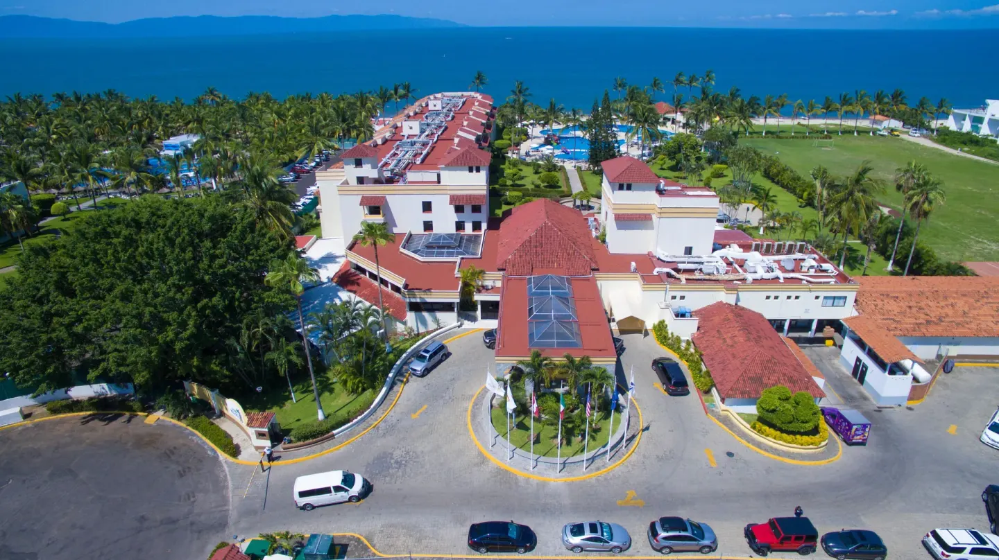 Aerial view of Samba Vallarta buildings, entrance road, gardens, pools, and oceanfront.