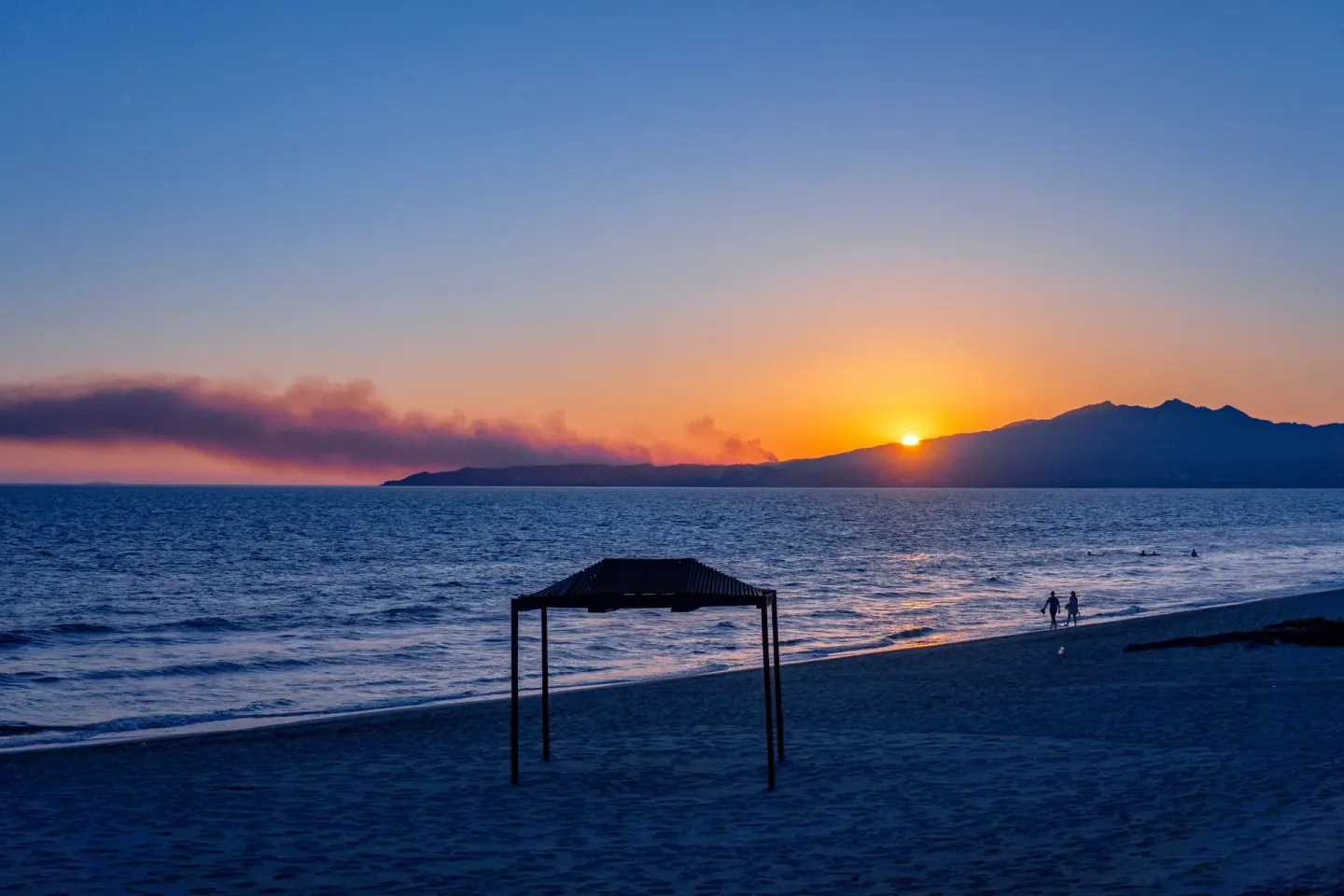 Sunset over the beach and bay at Samba Vallarta with a small shade structure on the sand.