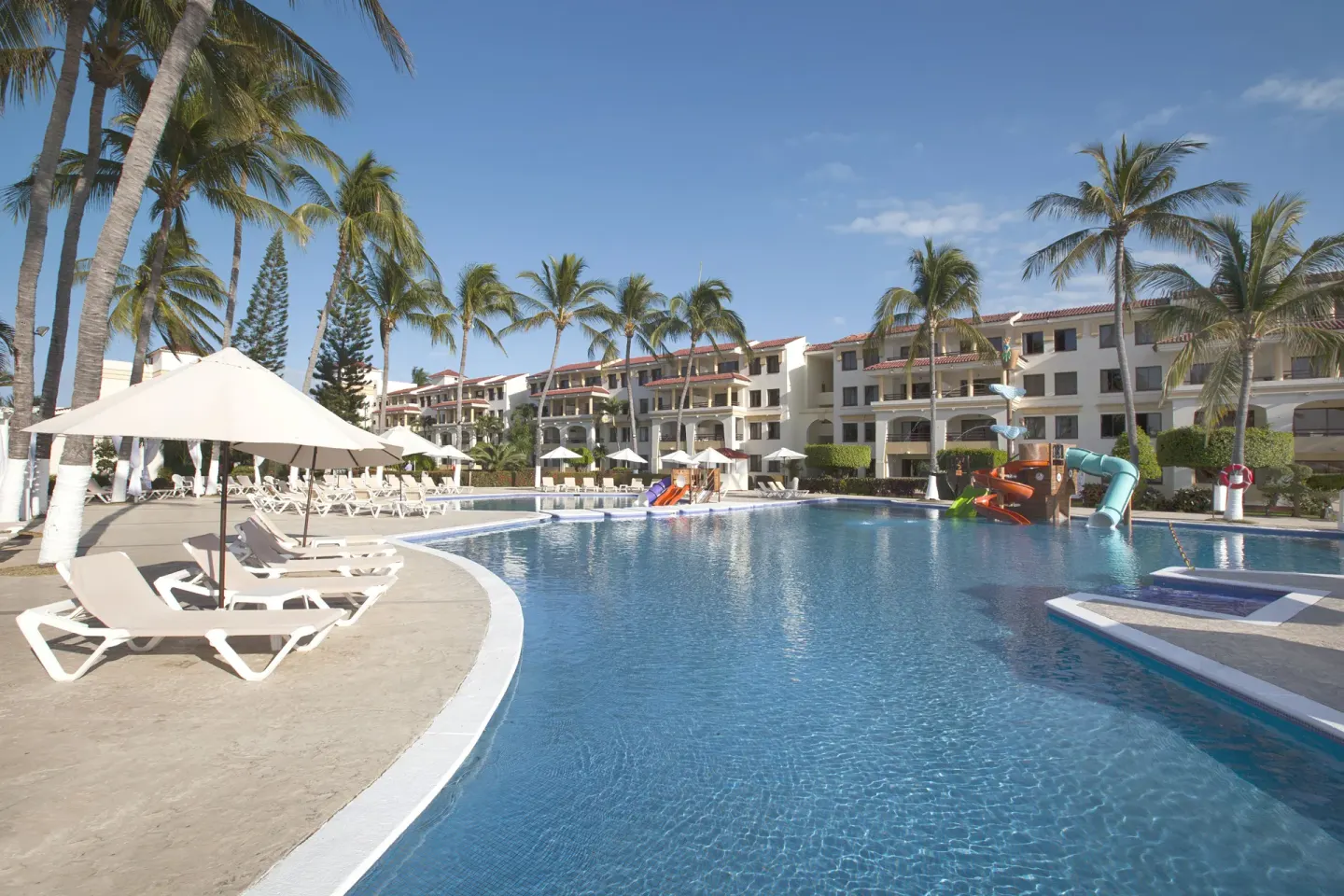 Curving pool with loungers, umbrellas, and slides at Samba Vallarta.