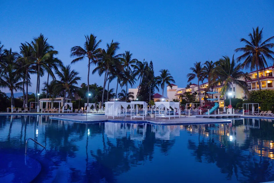 Evening pool with cabanas and palm trees at Samba Vallarta.