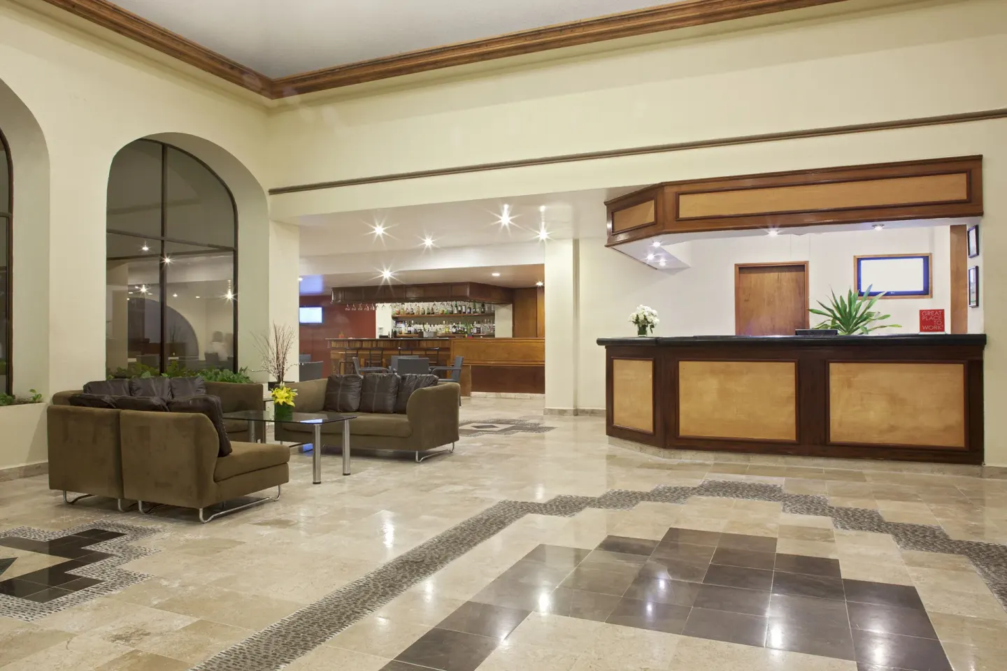 Lobby reception area with seating and a bar in the background at Samba Vallarta.