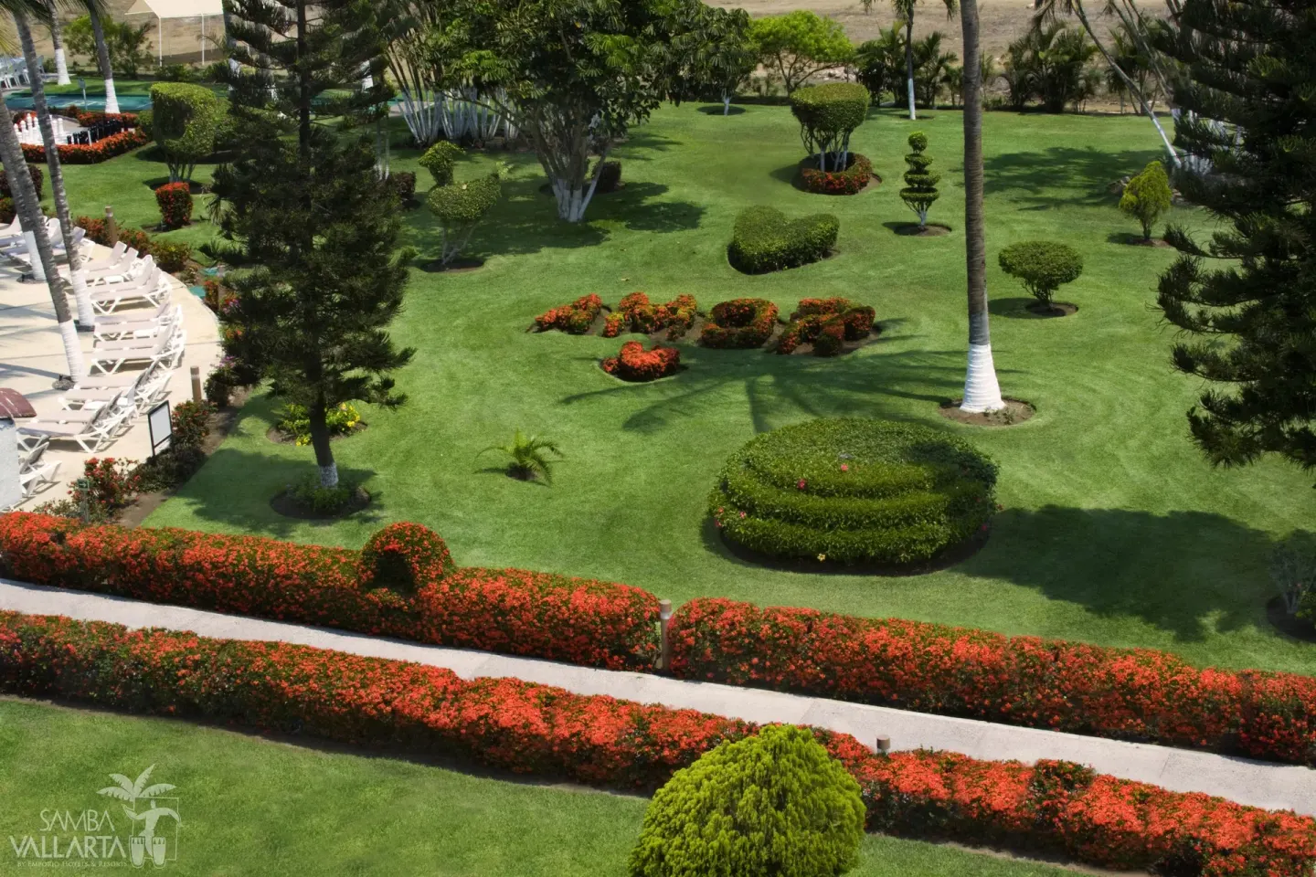 Manicured resort gardens with hedges, flowers, palms, and loungers at Samba Vallarta.