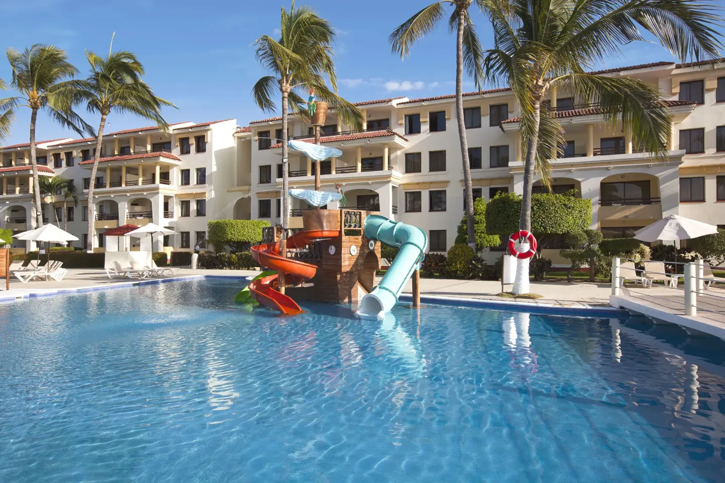 Pool with colorful slides and guest buildings at Samba Vallarta.