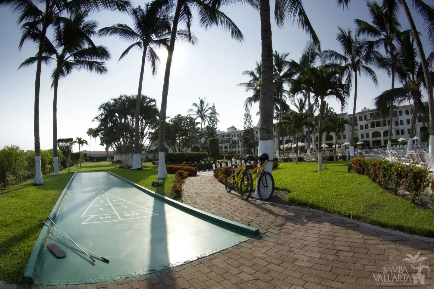Shuffleboard court and garden path beneath palm trees at Samba Vallarta.