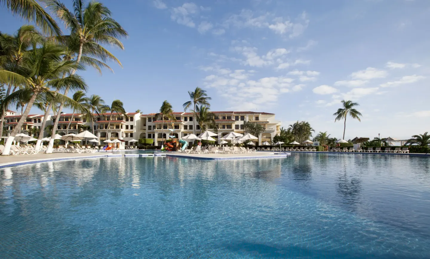 Wide daytime pool view with palms and loungers at Samba Vallarta.