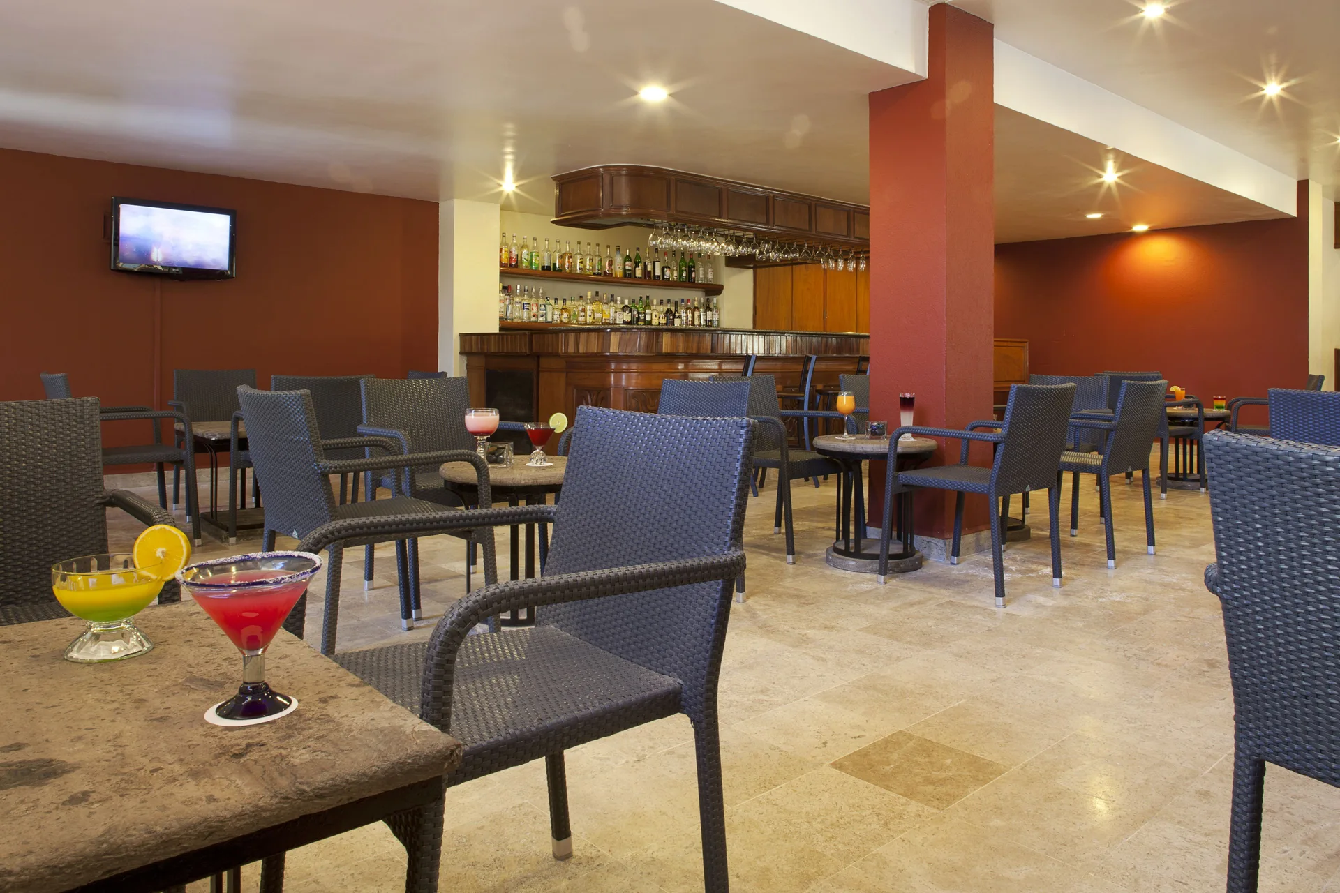Bar lounge with wicker chairs, small tables and cocktails at Samba Vallarta.
