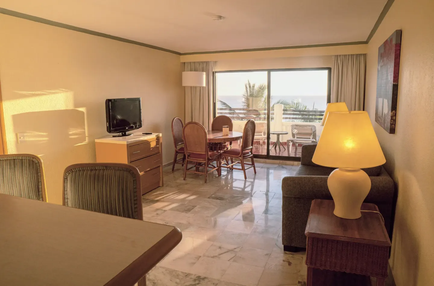 Junior Suite Ocean Front living room with balcony, dining table, sofa, and TV at Samba Vallarta.