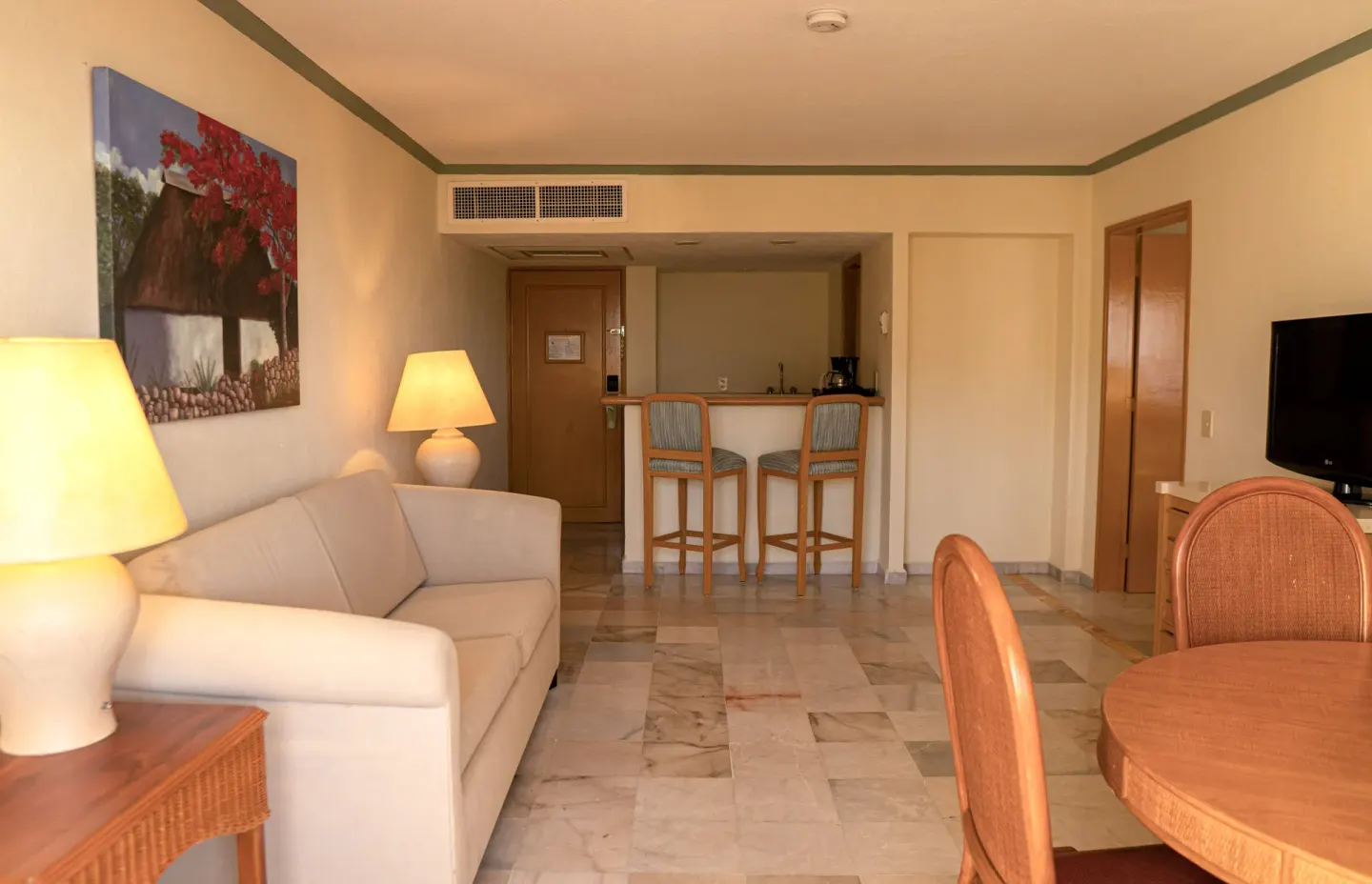 Junior Suite Ocean Front living area with sofa, round table, TV, and bar counter at Samba Vallarta.