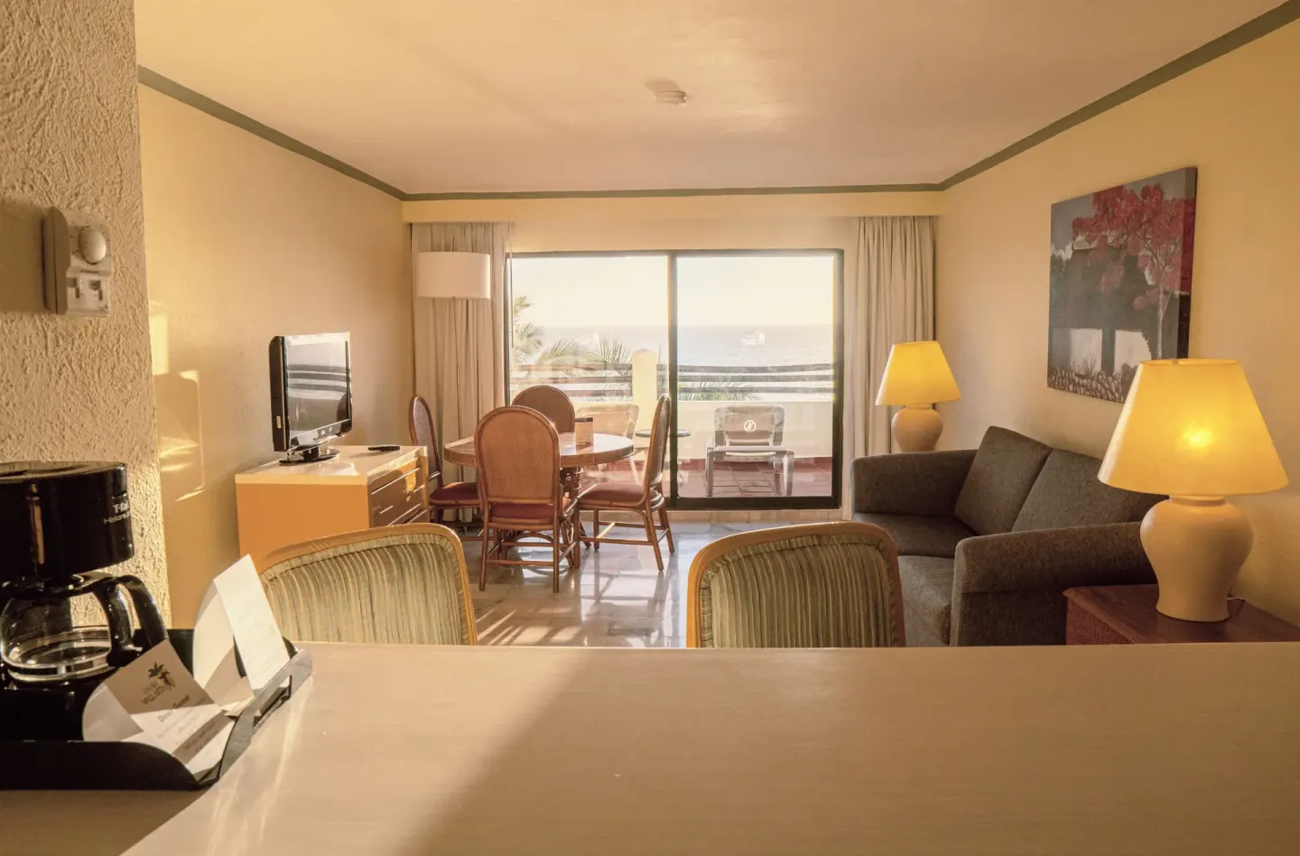 Junior Suite Ocean Front view from counter to sofa, dining table, TV, and balcony at Samba Vallarta.