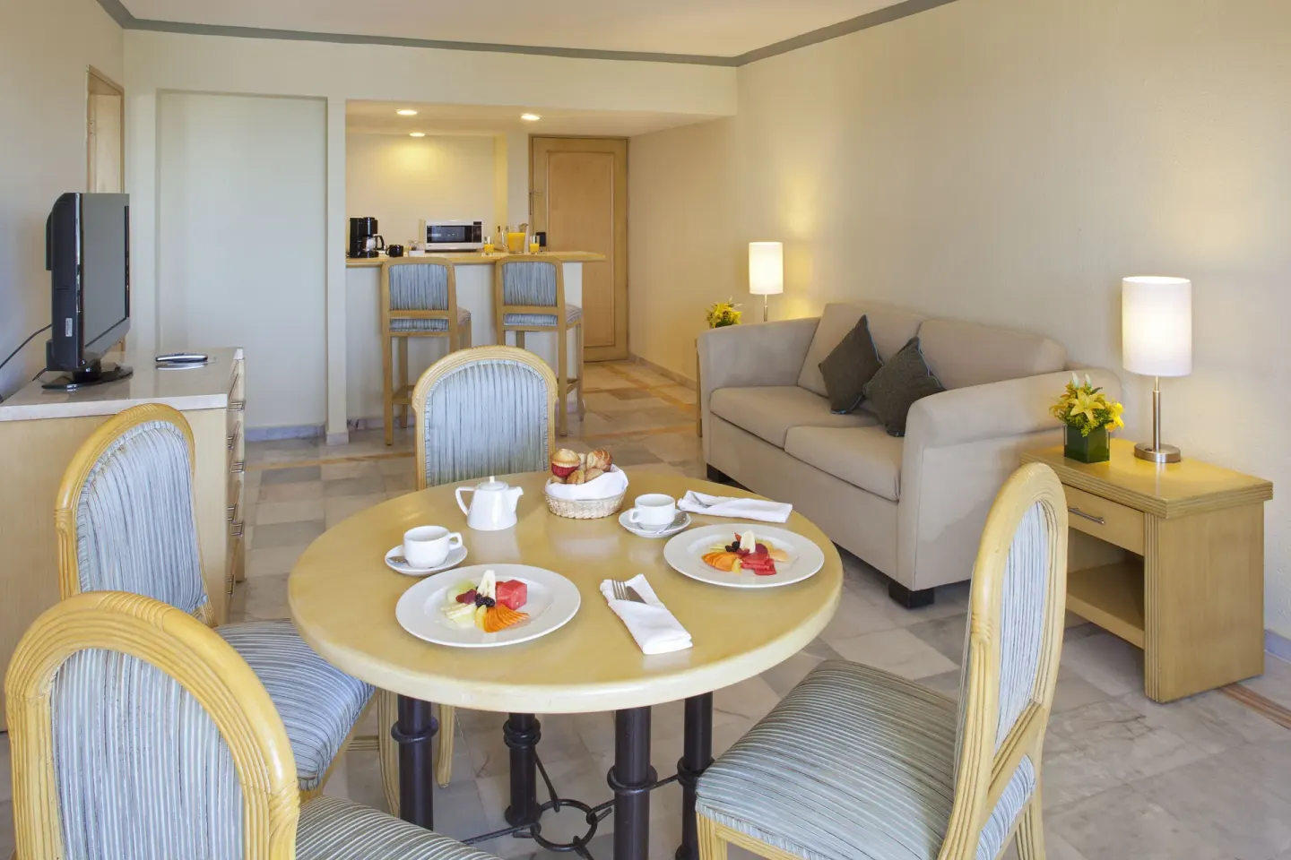 Junior Suite Ocean Front living and dining area at Samba Vallarta with sofa, table, TV, and kitchenette.
