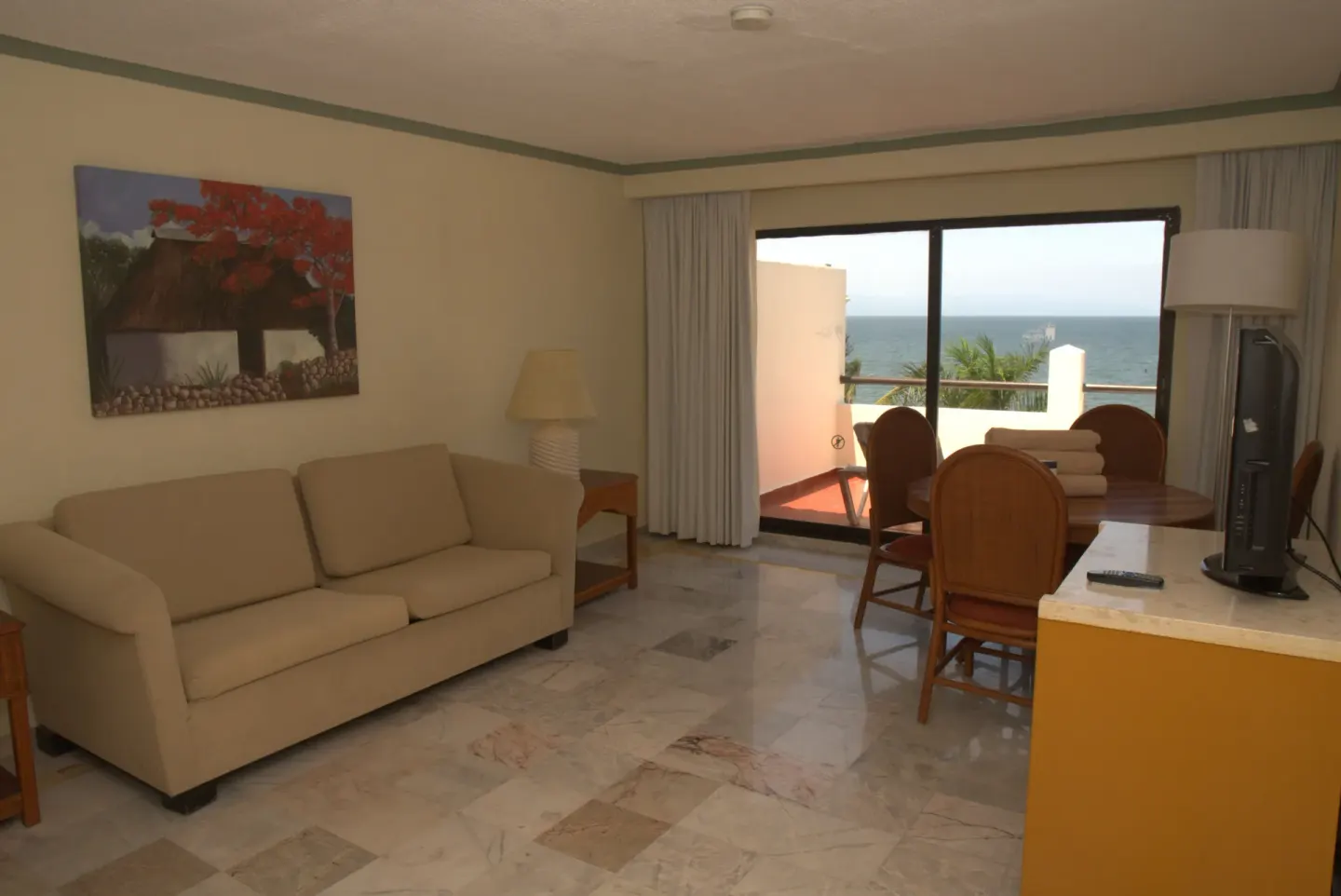 Junior Suite Ocean Front lounge with sofa, dining table, TV, and ocean balcony at Samba Vallarta.