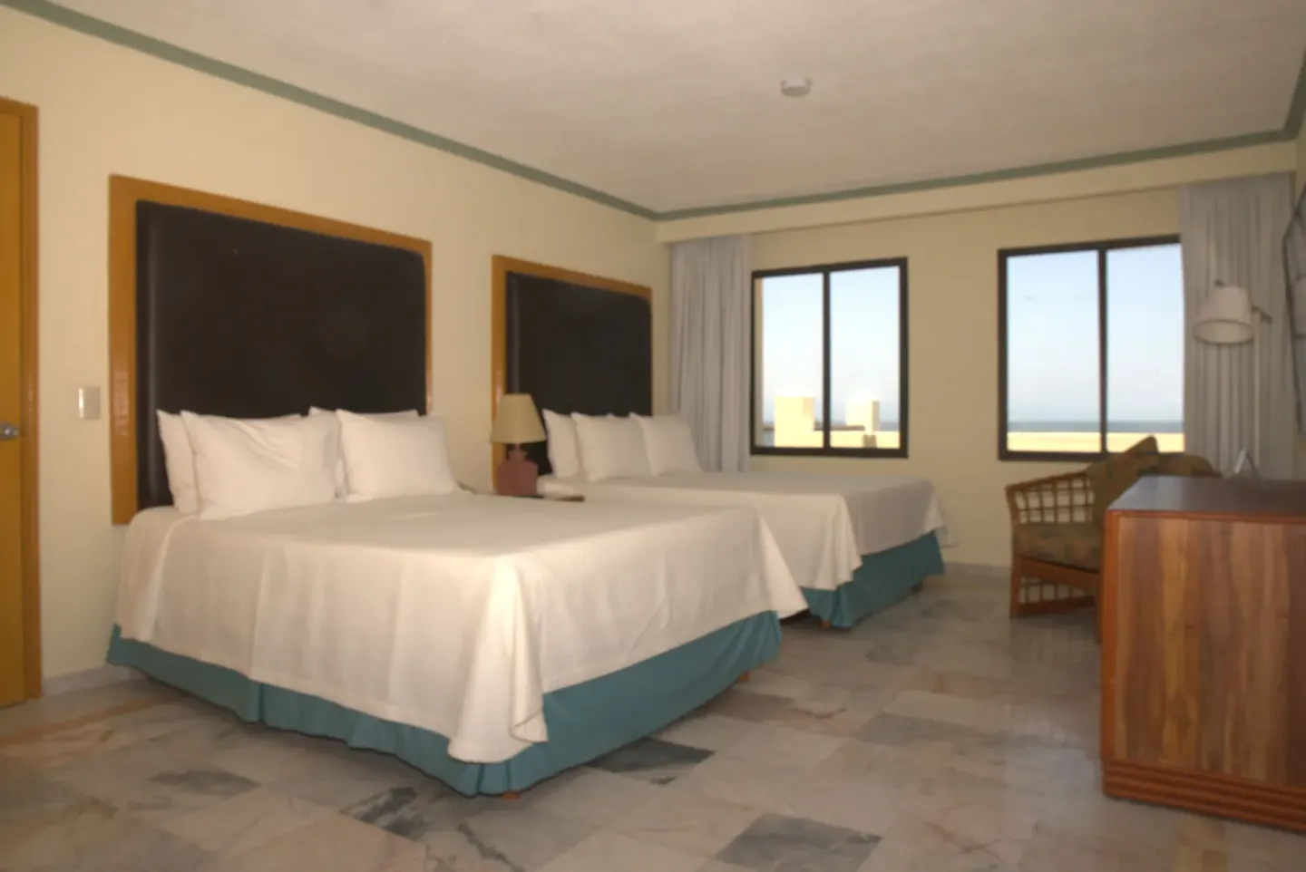 Junior Suite Ocean Front bedroom at Samba Vallarta with two beds, windows, seating, and dresser.