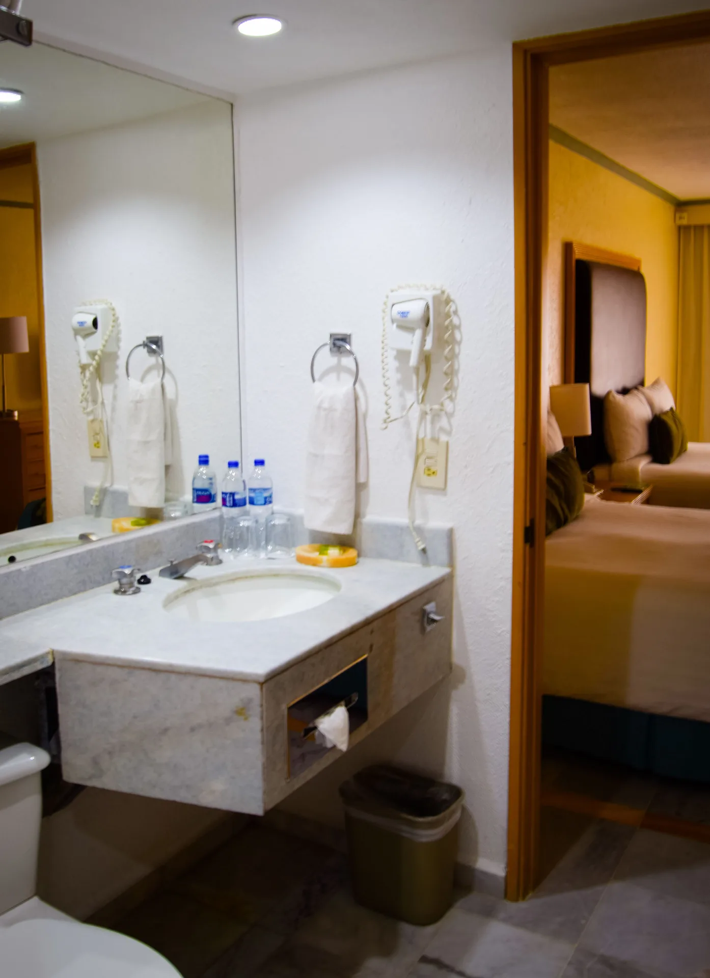 Standard Room bathroom vanity with mirror, sink, towels, and room doorway at Samba Vallarta.