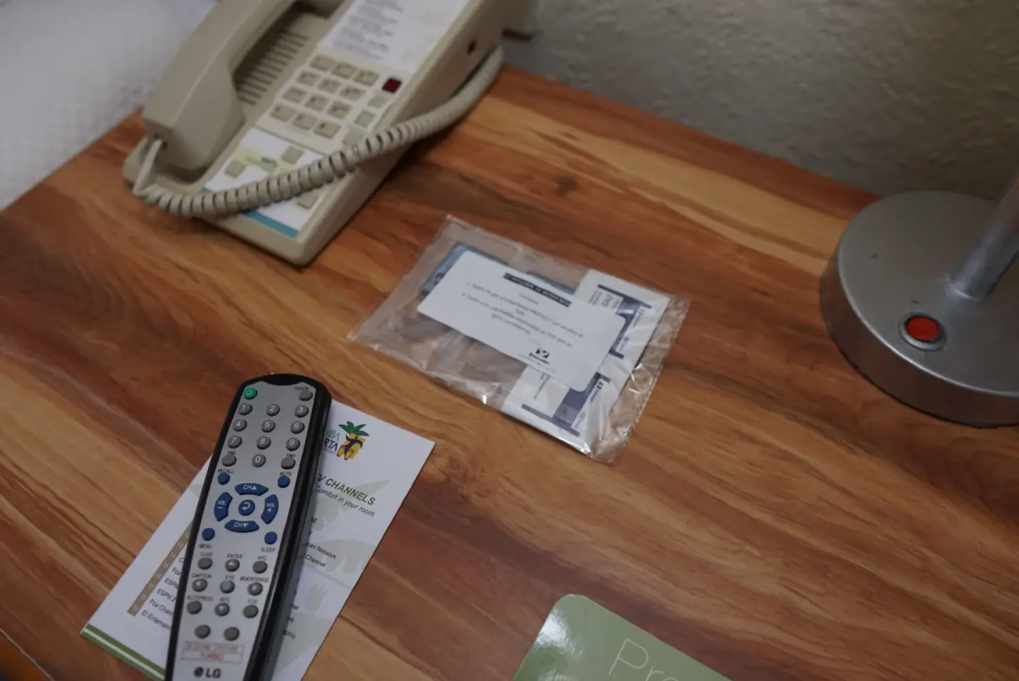Standard Room bedside table with phone, remote, lamp, and printed materials at Samba Vallarta.