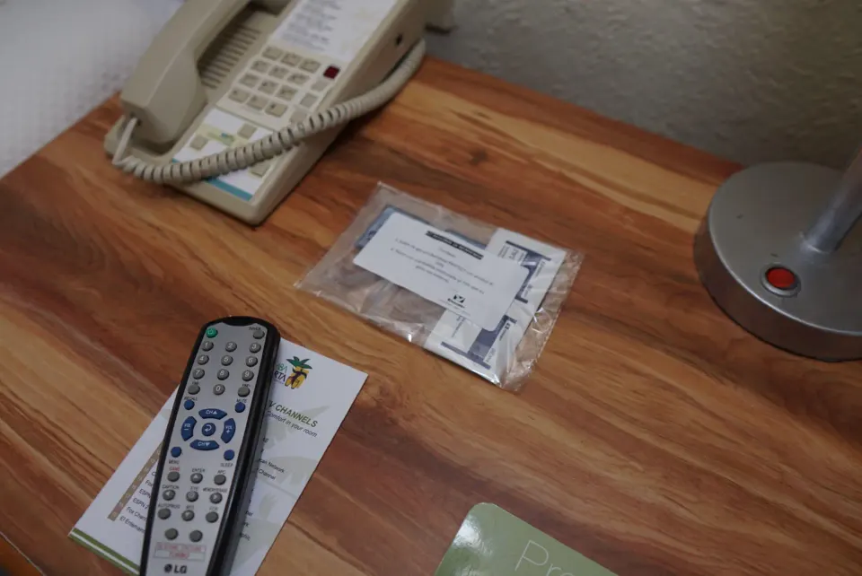 Standard Room bedside table with phone, remote, lamp, and printed materials at Samba Vallarta.