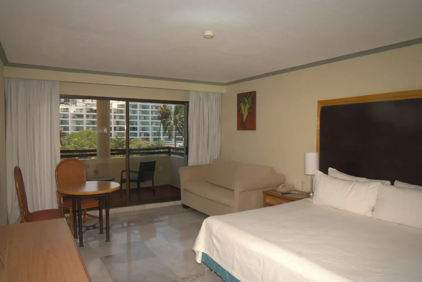 Standard Room with king bed, sofa, table, and balcony at Samba Vallarta.