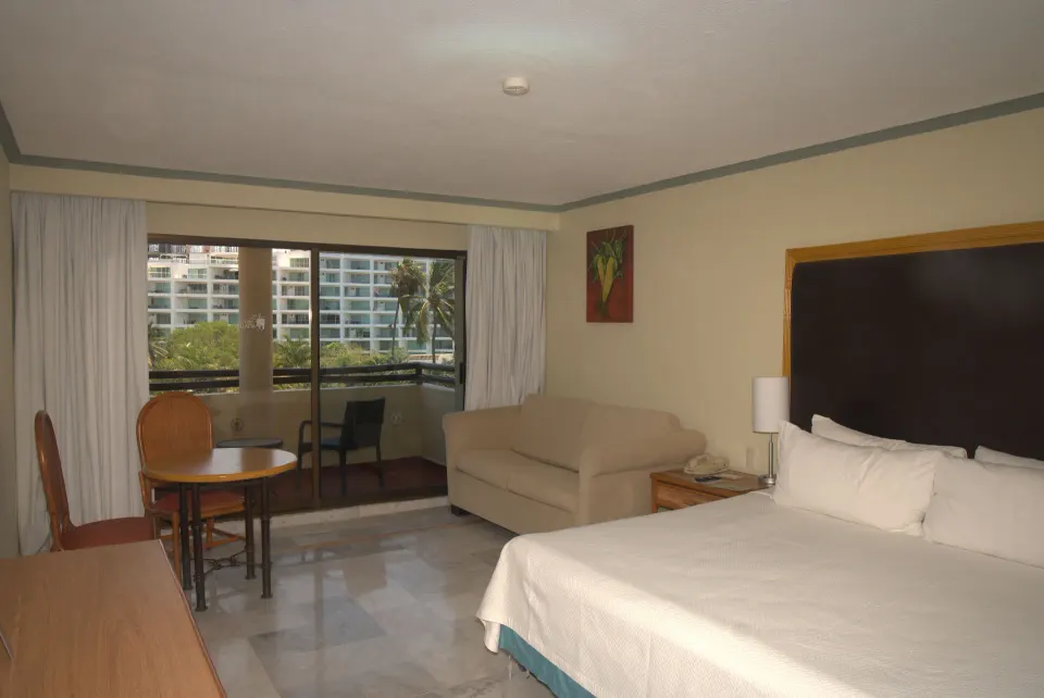 Standard Room with king bed, sofa, table, and balcony at Samba Vallarta.