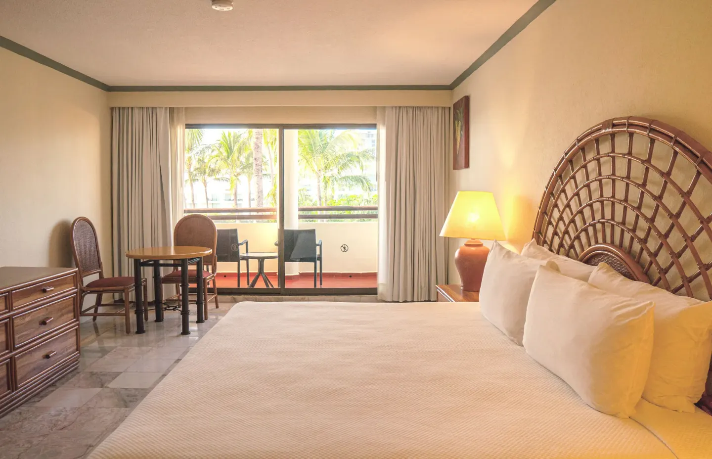 Standard Room with king bed, woven headboard, table, dresser, and balcony at Samba Vallarta.
