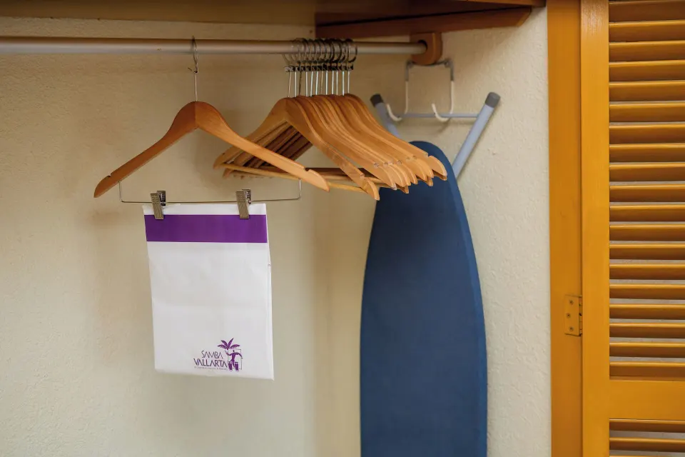 Standard Room closet with hangers, laundry bag, and ironing board at Samba Vallarta.