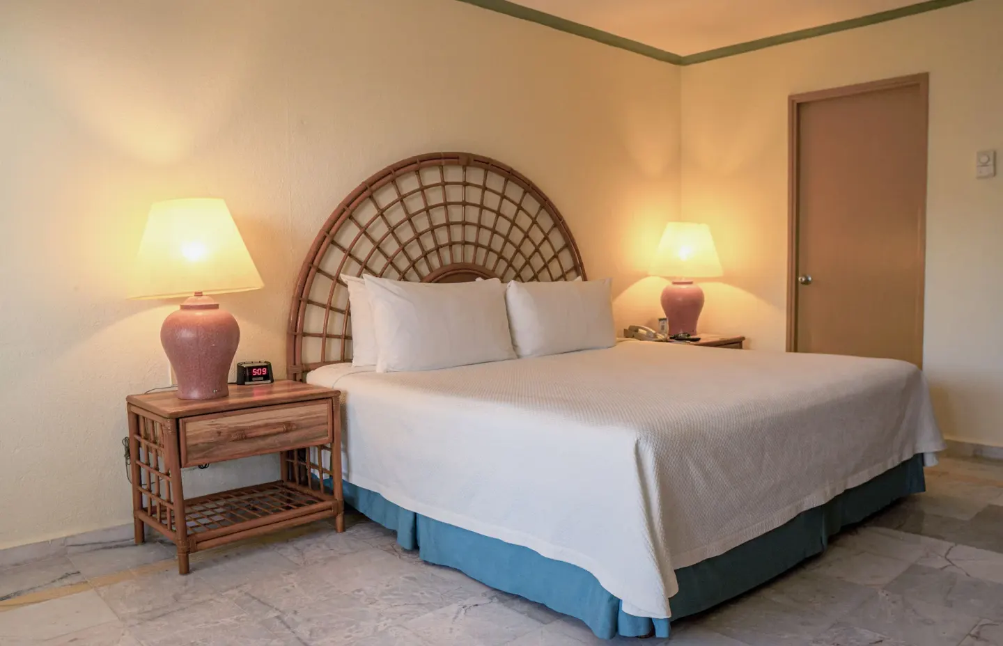 Standard Room with king bed, rattan headboard, and two bedside lamps at Samba Vallarta.