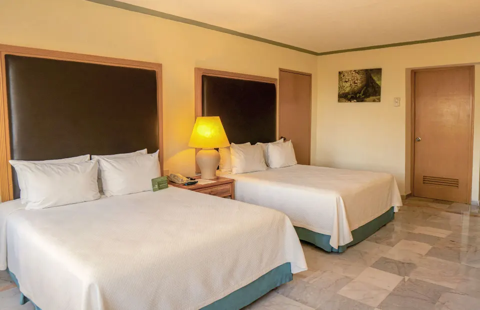 Standard Room with two beds, bedside lamp, and wood doors at Samba Vallarta.