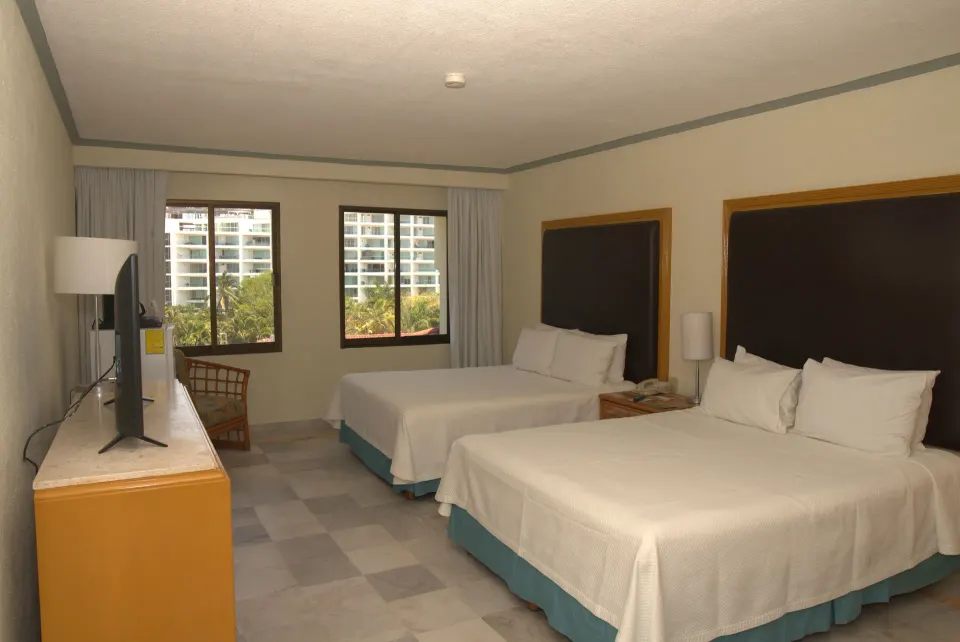 Standard Room with two beds, TV, windows, and desk chair at Samba Vallarta.
