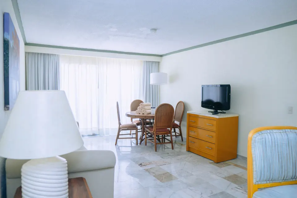 Suite terrace living area with dining table, TV, and wicker seating at Samba Vallarta.