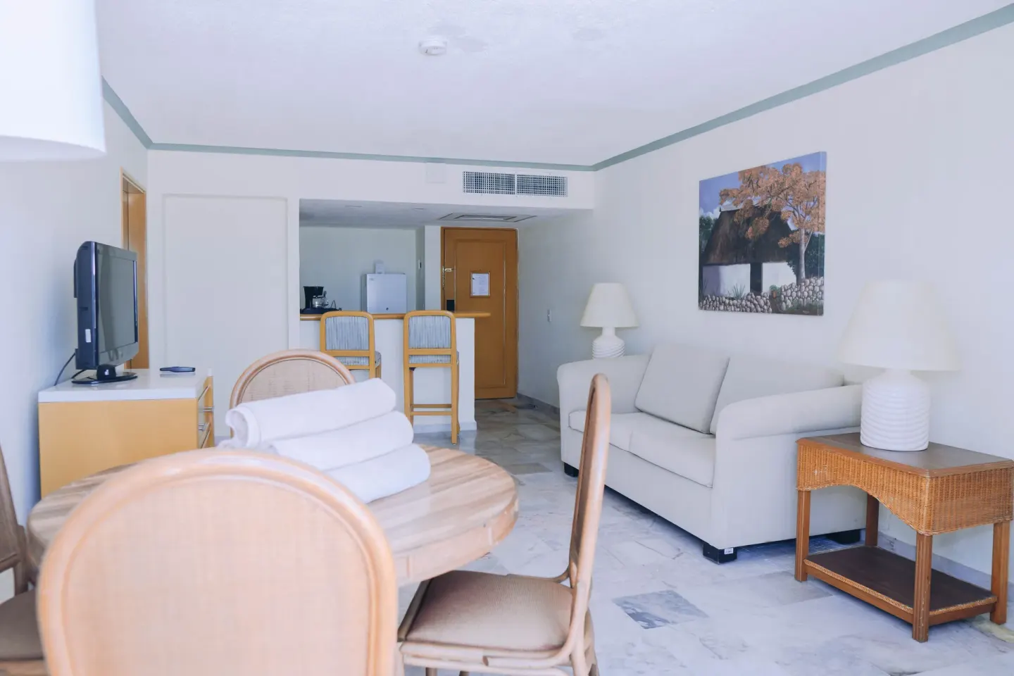 Suite terrace sitting room with sofa, dining table, TV, and kitchenette area at Samba Vallarta.