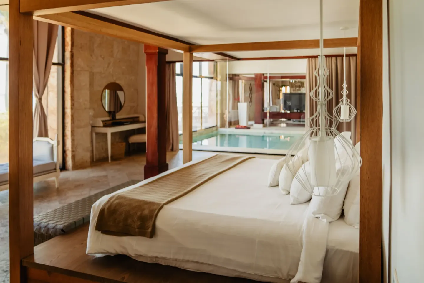 Canopy king bed beside an indoor pool at Sanctuary Cap Cana, a Luxury Collection Resort.