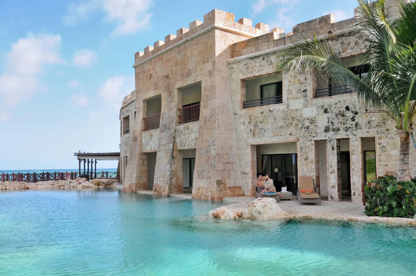 Stone castle-style building by a turquoise pool at Sanctuary Cap Cana, a Luxury Collection Resort.