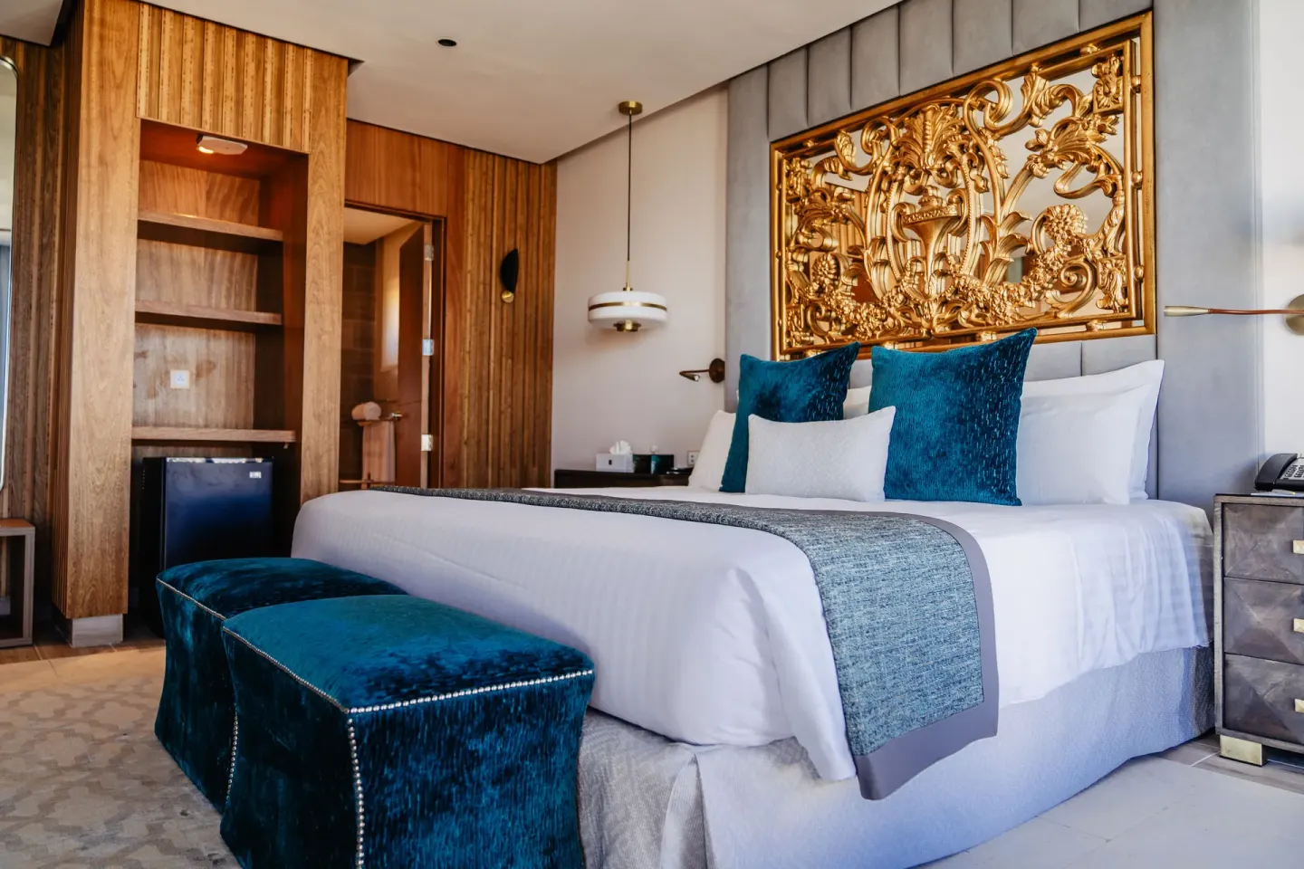 Guest room with a king bed, teal accents, and ornate gold headboard at Sanctuary Cap Cana, a Luxury Collection Resort.