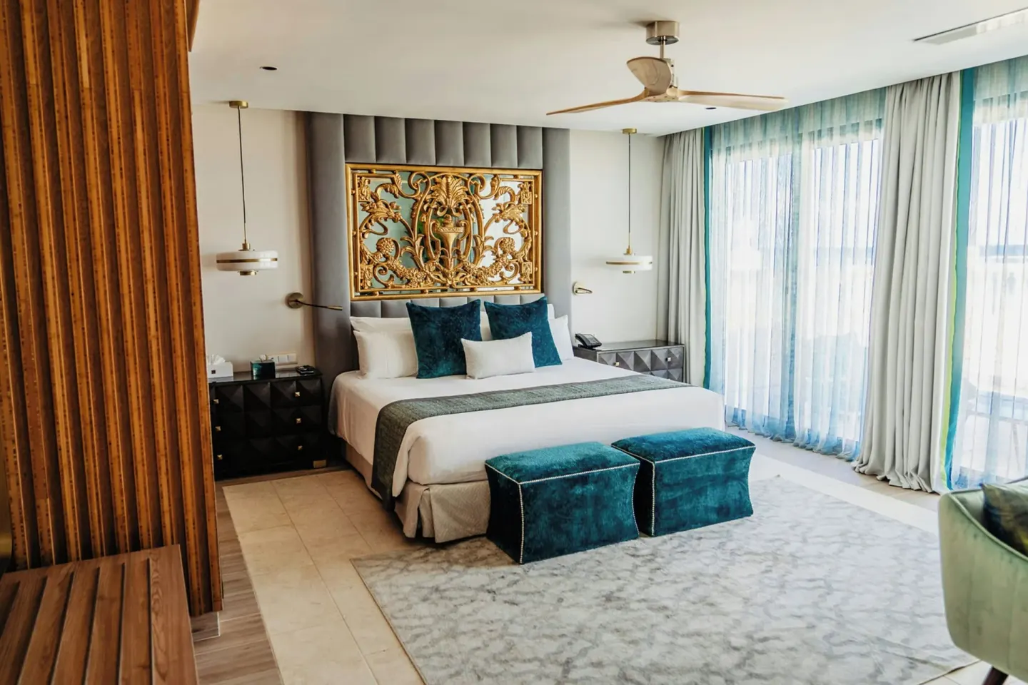 Guest room with king bed, teal accents, and ornate headboard at Sanctuary Cap Cana, a Luxury Collection Resort.