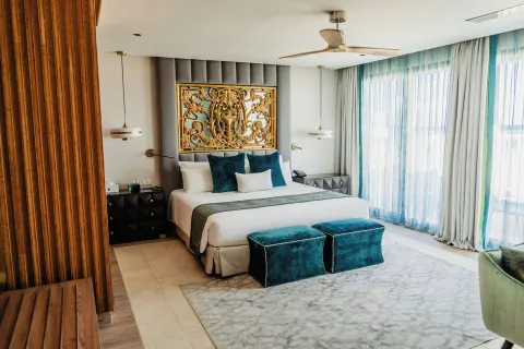Guest room with king bed, teal accents, and ornate headboard at Sanctuary Cap Cana, a Luxury Collection Resort.
