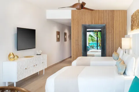 Twin-bed guest room with balcony glimpse at Sanctuary Cap Cana, a Luxury Collection Resort.