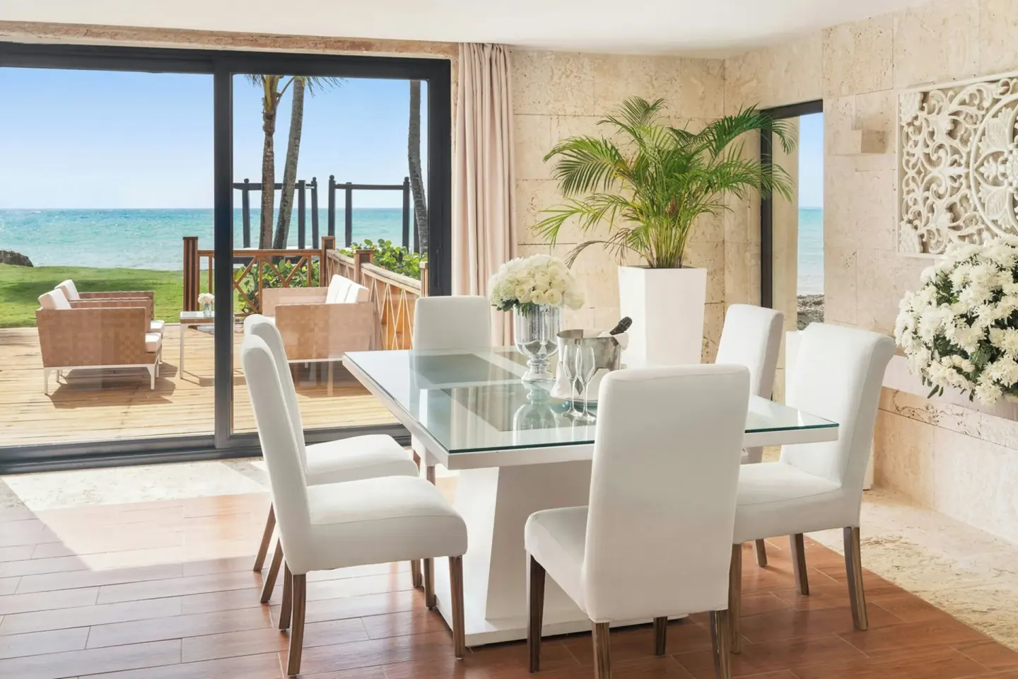 Dining area with glass table and oceanfront deck at Sanctuary Cap Cana, a Luxury Collection Resort.