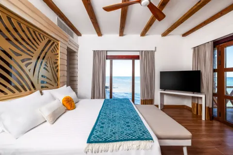 Oceanfront guest room with king bed and wood-beamed ceiling at Sanctuary Cap Cana, a Luxury Collection Resort.