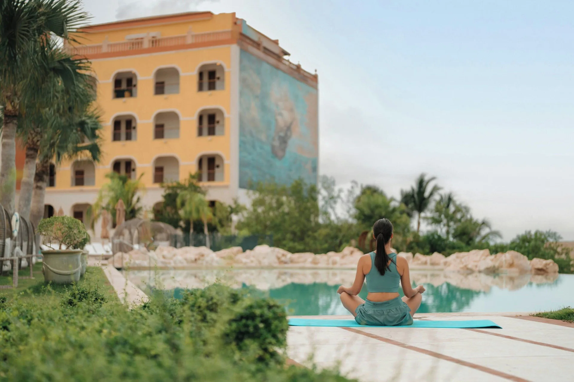 A guest meditates beside a pool at Sanctuary Cap Cana, a Luxury Collection Resort.