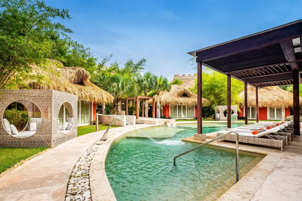 Spa pool with thatched cabanas and loungers at Sanctuary Cap Cana, a Luxury Collection Resort.