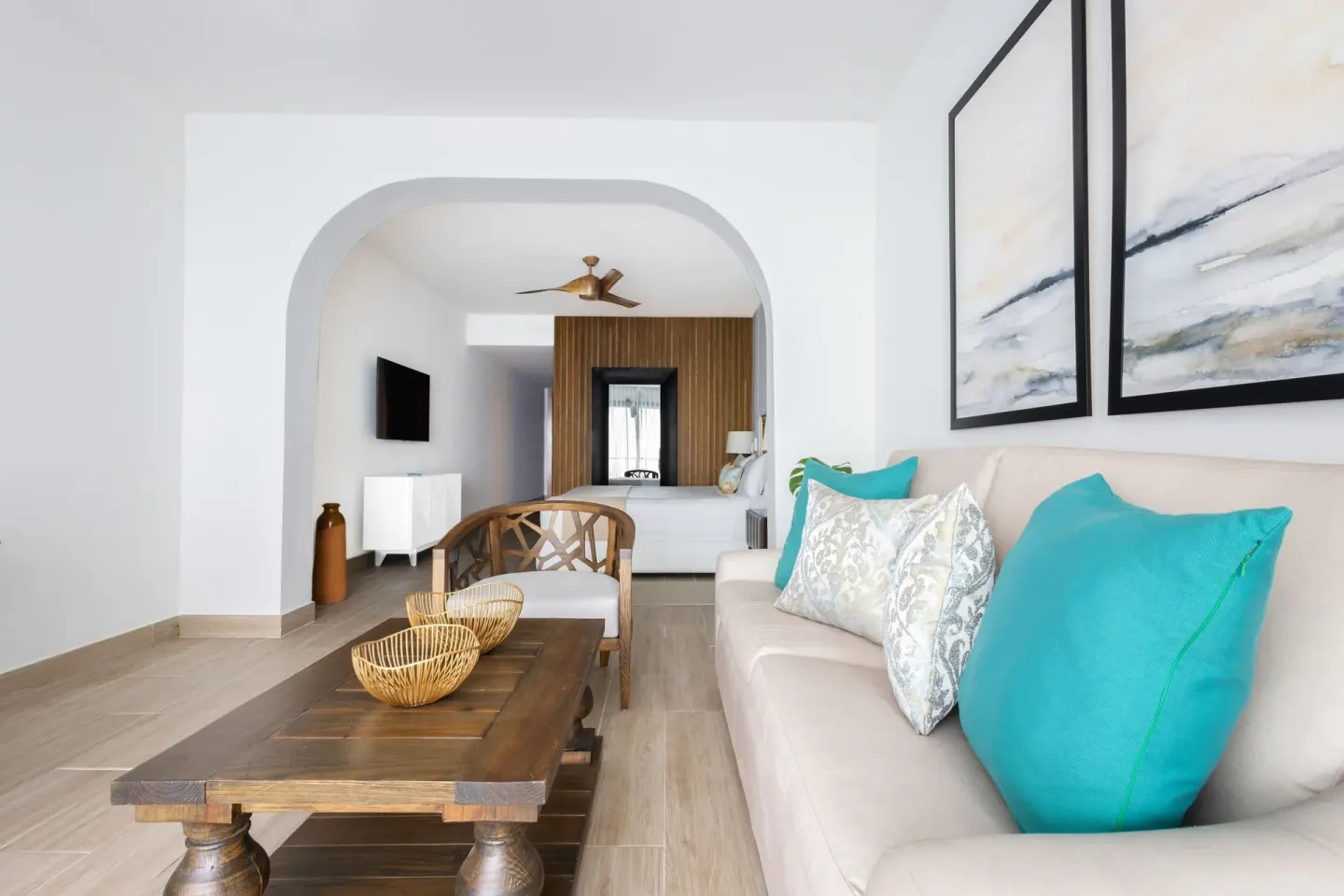 Suite sitting area with sofa and bedroom beyond at Sanctuary Cap Cana, a Luxury Collection Resort.