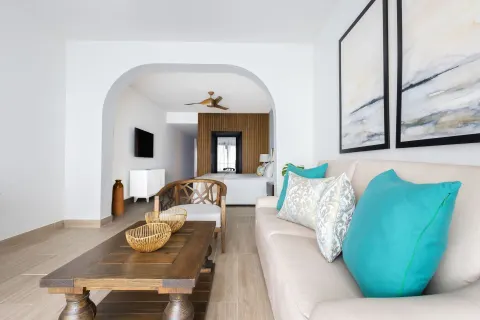 Suite sitting area with sofa and bedroom beyond at Sanctuary Cap Cana, a Luxury Collection Resort.
