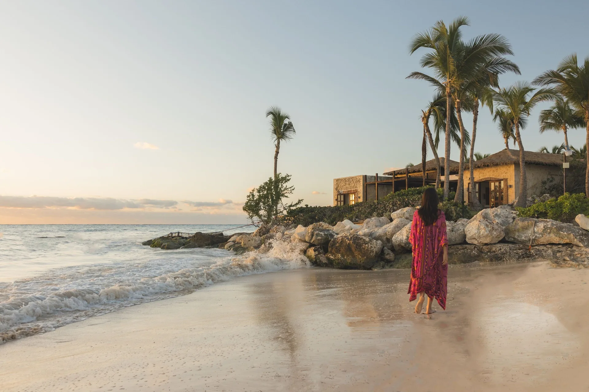 Guest walking along the beach at sunset at Sanctuary Cap Cana, a Luxury Collection Resort.