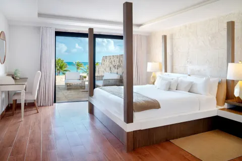 Four-poster king bed with terrace view at Sanctuary Cap Cana, a Luxury Collection Resort.