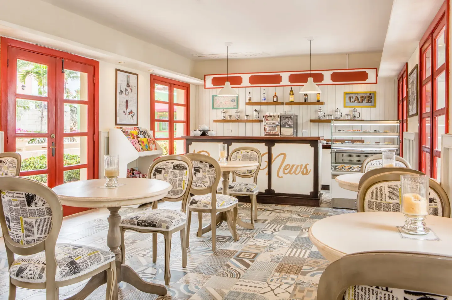 Coffee shop with red doors, café tables, and pastry case at Sanctuary Cap Cana, a Luxury Collection Resort.