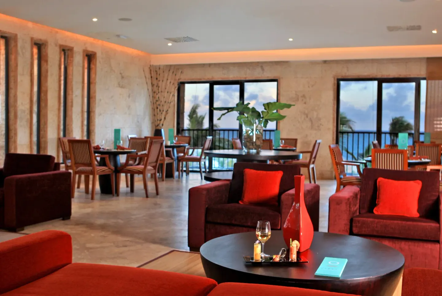 A lounge-style dining room with red seating at Sanctuary Cap Cana, a Luxury Collection Resort.