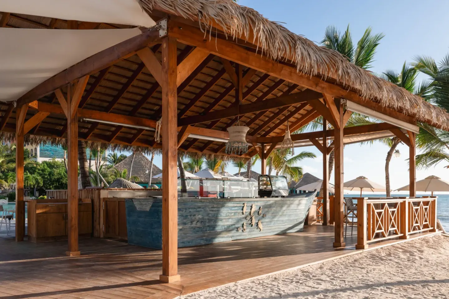 Thatched beach bar with a boat-shaped counter at Sanctuary Cap Cana, a Luxury Collection Resort.