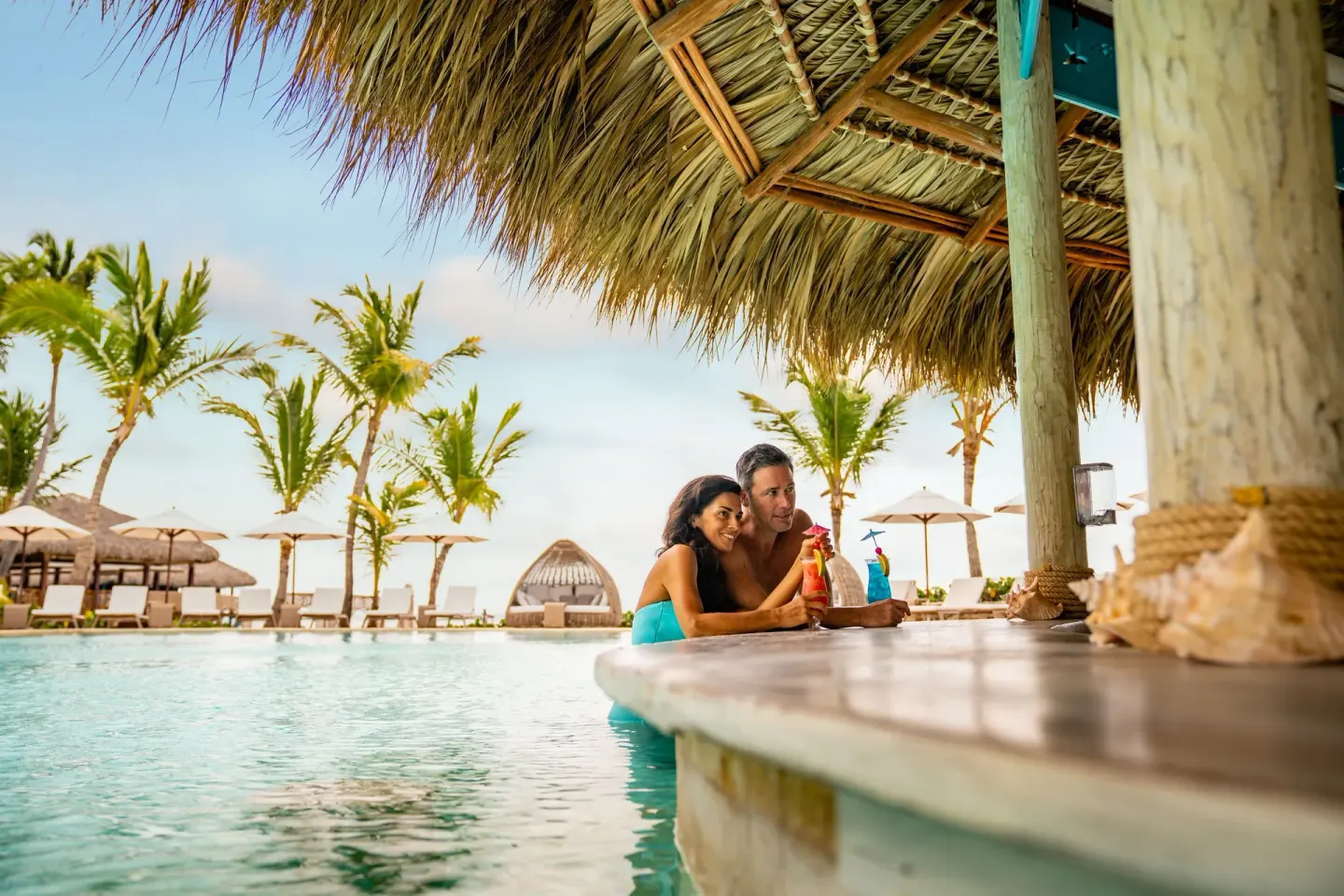 Guests at a thatched swim-up bar at Sanctuary Cap Cana, a Luxury Collection Resort.
