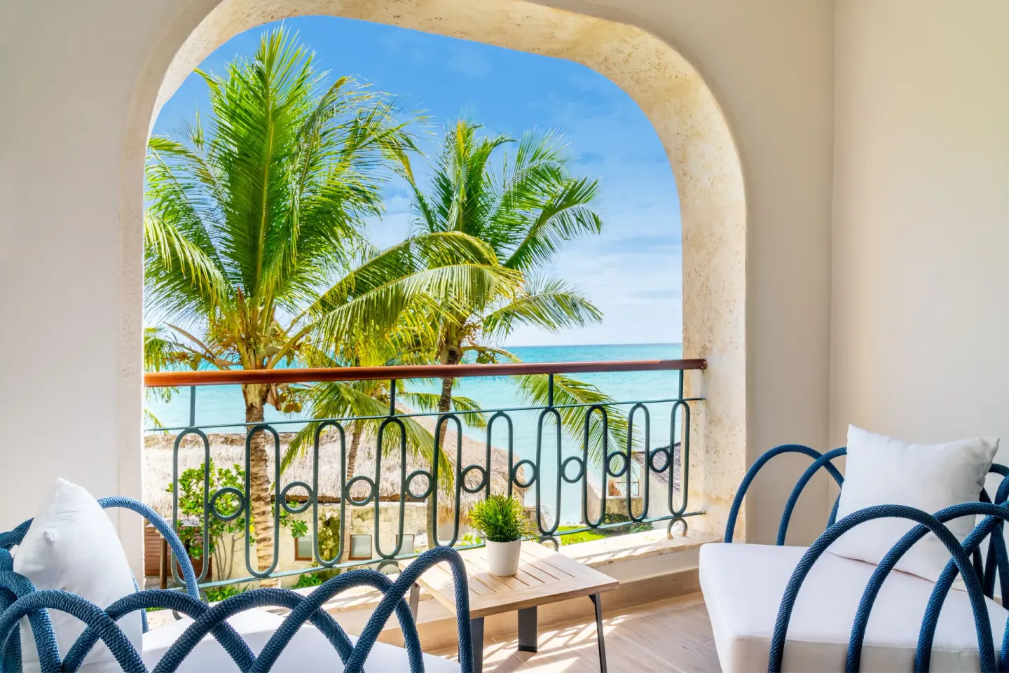 Balcony seating and palm-framed ocean view at Sanctuary Cap Cana, a Luxury Collection Resort.