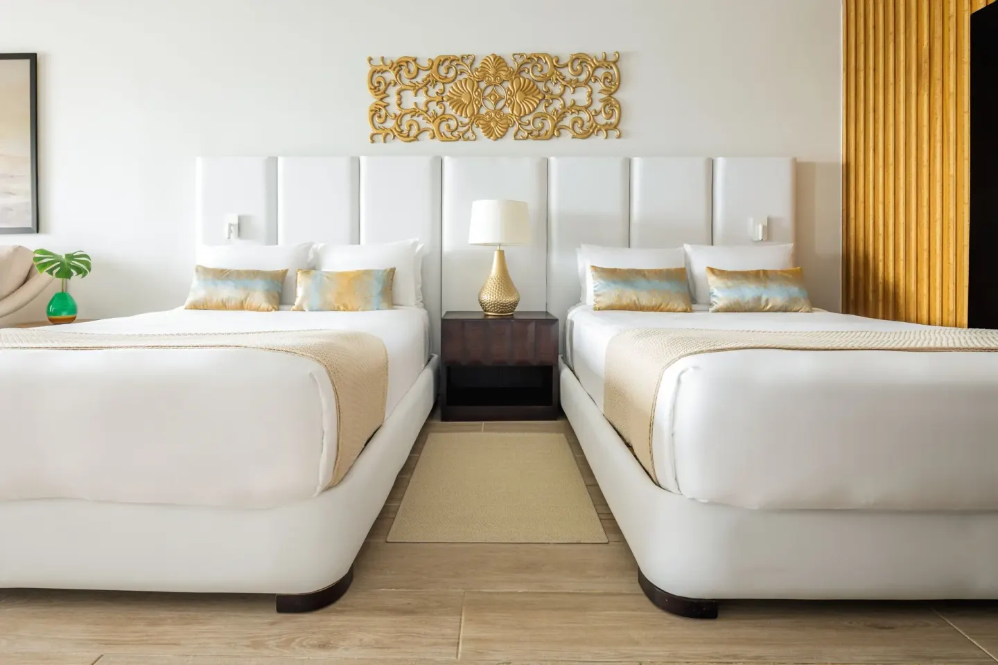 Two white beds with gold wall decor in a Junior Room at Sanctuary Cap Cana, a Luxury Collection Resort.