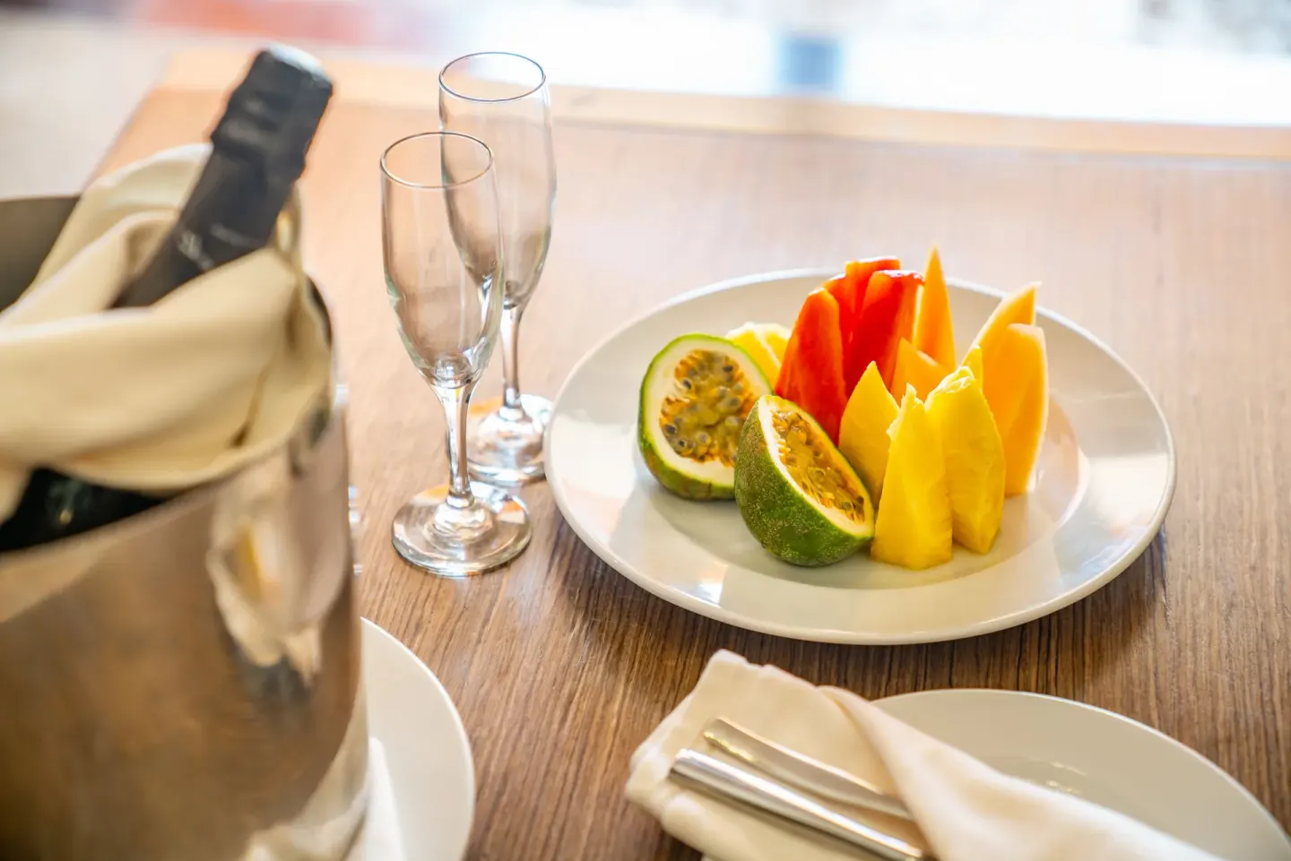 Fruit plate, champagne flutes, and chilled bottle in a suite at Sanctuary Cap Cana, a Luxury Collection Resort.